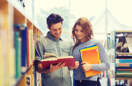 happy student couple with books in library